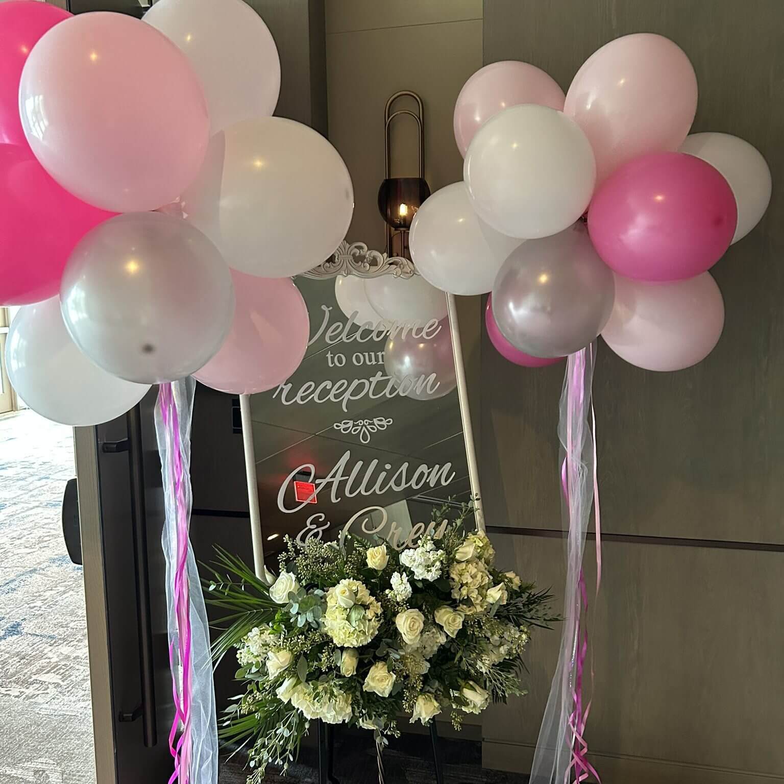 Wedding reception sign with balloons and flowers.