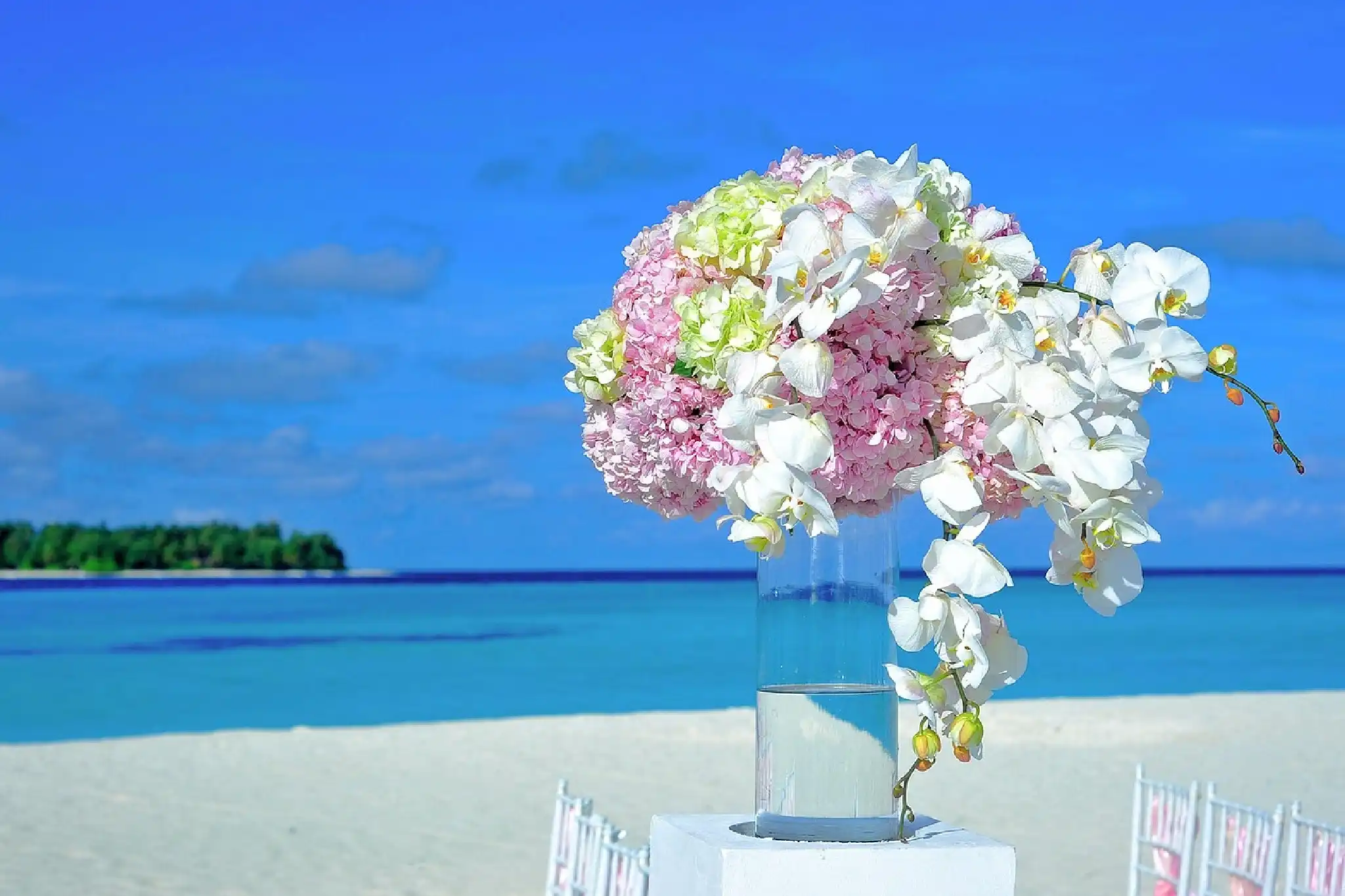 Elegant floral arrangement by the beach under a clear blue sky.