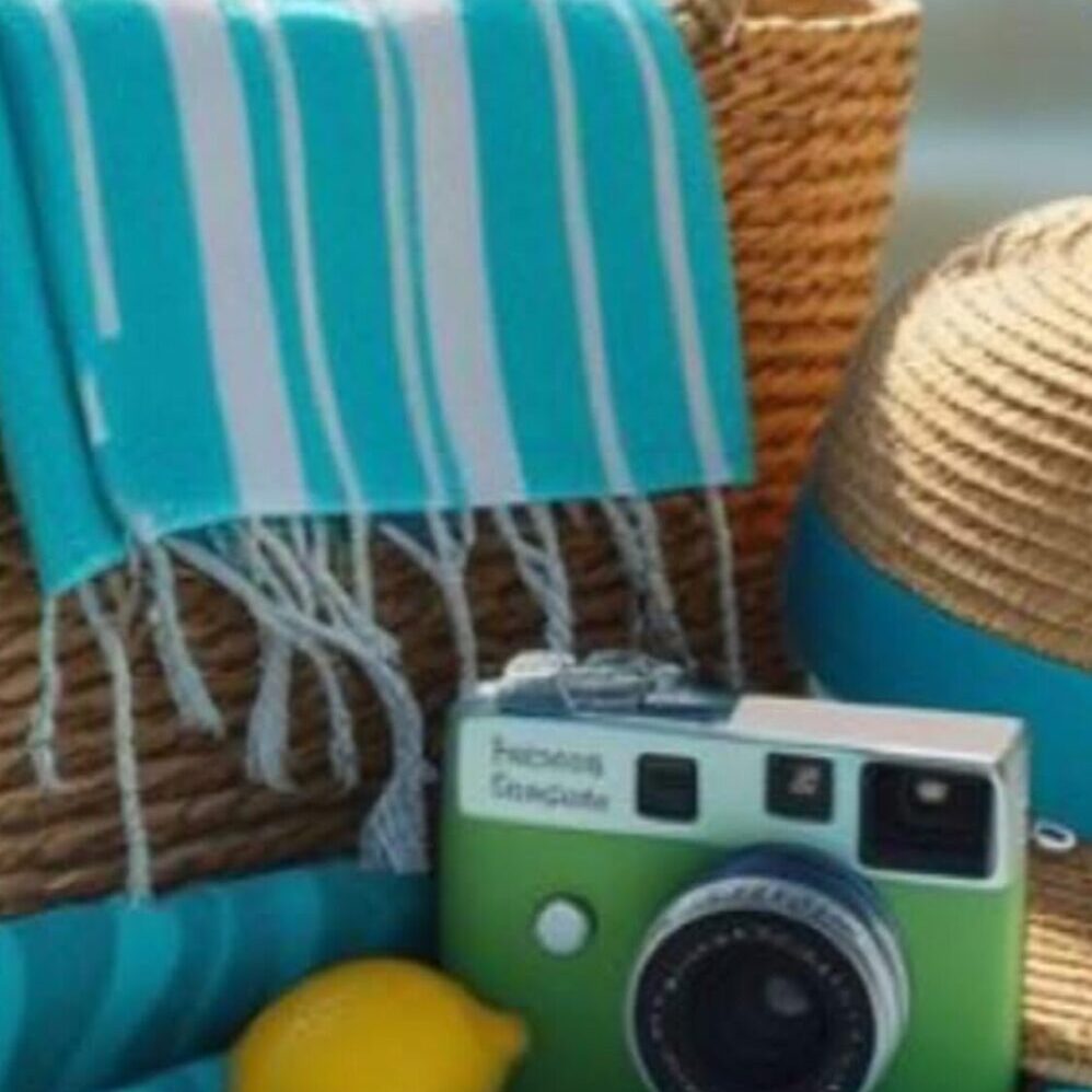 A vintage camera with a blue striped towel and wicker basket.
