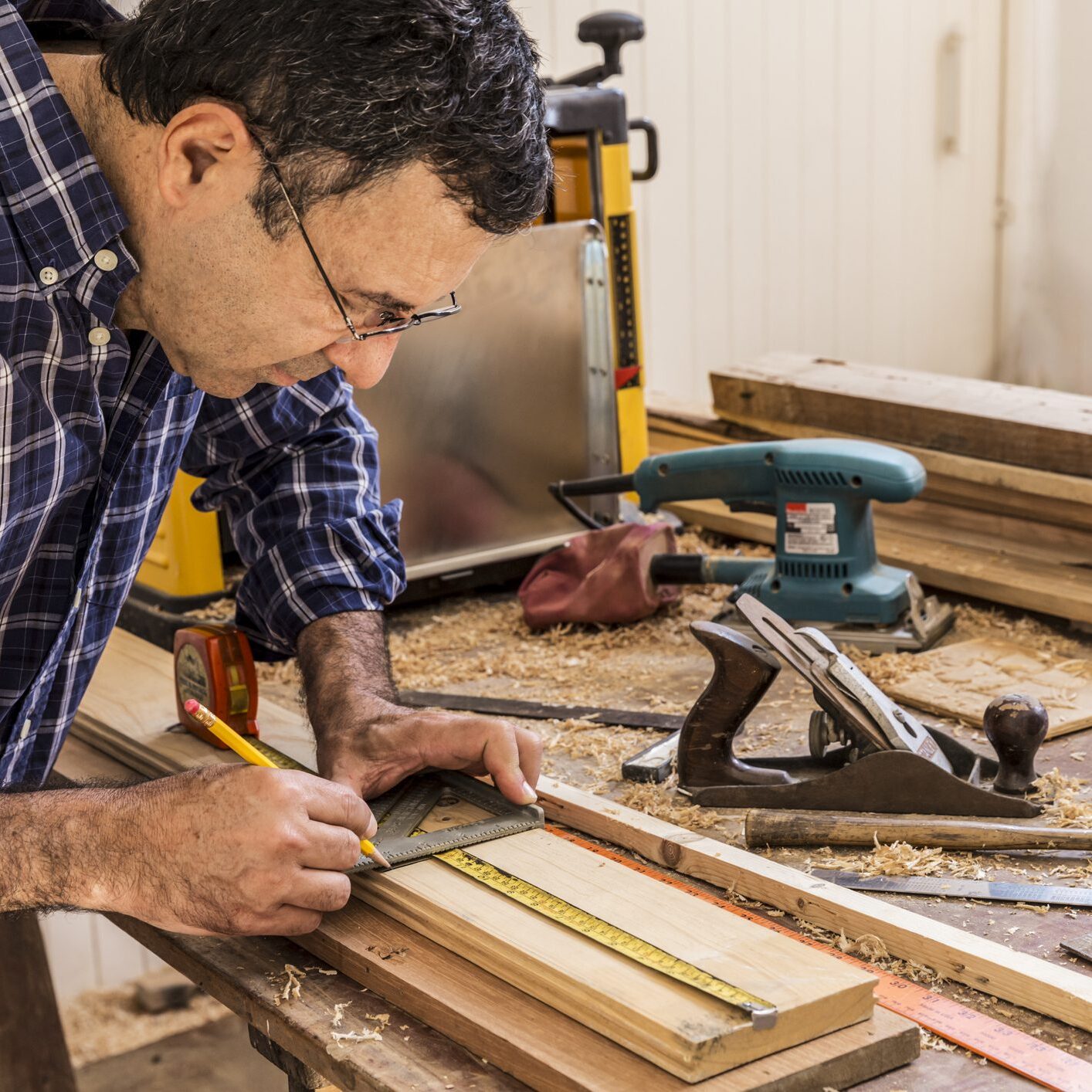 Man crafting wood pieces in a workshop.